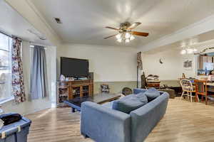 Living room with crown molding, light hardwood / wood-style floors, and a healthy amount of sunlight