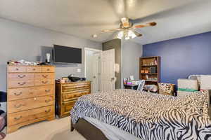 Bedroom with light carpet, ceiling fan, and a textured ceiling