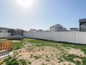 View of yard featuring a trampoline, a residential view, and a fenced backyard