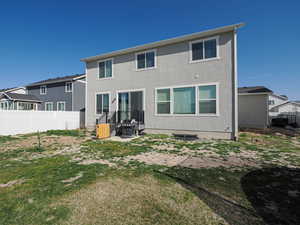Back of property featuring a yard, stucco siding, and fence