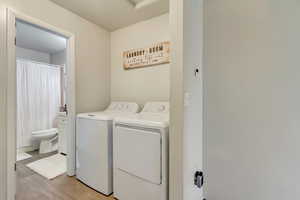 Clothes washing area featuring washing machine and dryer and light hardwood / wood-style flooring