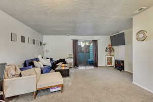 Living room with a wood stove, carpet, and a textured ceiling