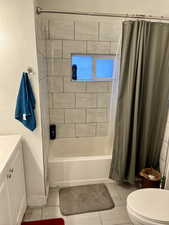 Full bathroom with vanity, tile patterned flooring, toilet, and shower / bath combo with shower curtain