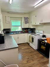 Kitchen featuring a textured ceiling, white cabinetry, sink, white range with electric stovetop, and dark hardwood / wood-style flooring