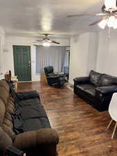 Living room featuring dark hardwood / wood-style flooring, ceiling fan, and a textured ceiling