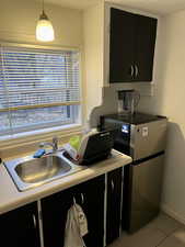 Kitchen with hanging light fixtures, sink, light tile patterned floors, and stainless steel fridge