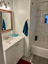 Bathroom featuring vanity, tile patterned floors, and tiled shower / bath