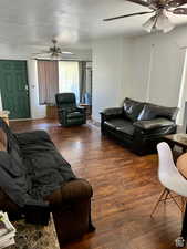 Living room featuring dark wood-type flooring, a textured ceiling, and ceiling fan