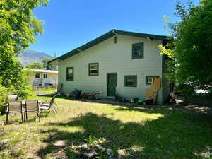 Back of property featuring a mountain view and a lawn