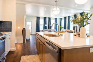 Kitchen featuring decorative light fixtures, stainless steel appliances, an island with sink, decorative backsplash, and sink