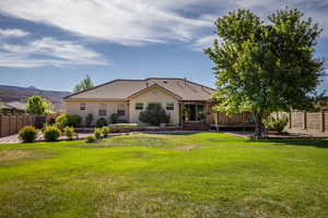 Rear view of property with a mountain view and a lawn