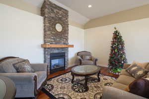 Living room with hardwood / wood-style floors, lofted ceiling, and a fireplace