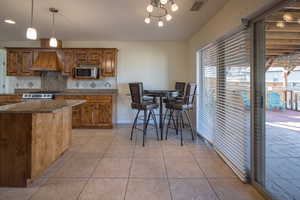 Kitchen with pendant lighting, dark stone counters, backsplash, custom range hood, and stove