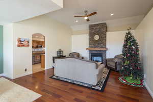 Living room with a fireplace, ceiling fan, dark hardwood / wood-style floors, and lofted ceiling