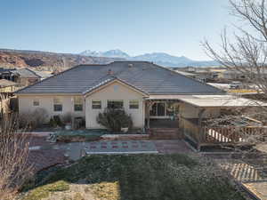 Rear view of house with a mountain view and a lawn