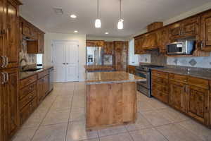 Kitchen with appliances with stainless steel finishes, sink, custom exhaust hood, tasteful backsplash, and a center island