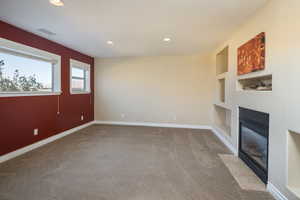 Unfurnished living room with built in features and light carpet