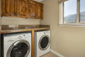 Washroom with a mountain view, light tile patterned floors, separate washer and dryer, and cabinets