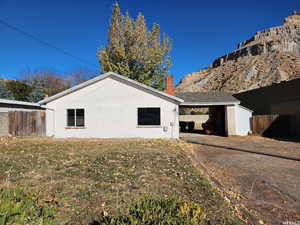 View of side of property featuring a carport and a lawn