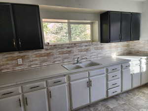 Kitchen with sink, white cabinetry, and decorative backsplash