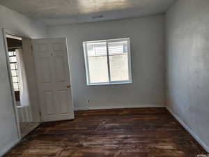 Spare room with dark wood-type flooring and a textured ceiling