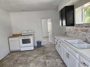 Kitchen featuring sink, white range with electric stovetop, and white cabinetry