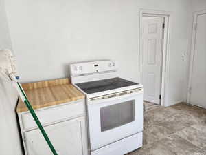 Kitchen featuring white cabinetry and electric range