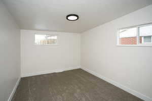 Basement featuring dark colored carpet and a textured ceiling