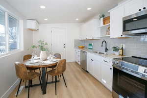 Kitchen with sink, stainless steel appliances, light stone counters, and white cabinets