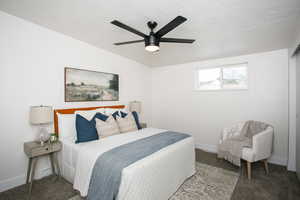 Carpeted bedroom featuring ceiling fan and a textured ceiling