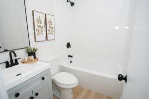 Full bathroom featuring wood-type flooring, shower / bath combination, toilet, and vanity