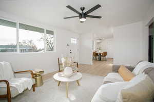 Living room featuring a wall mounted AC, light hardwood / wood-style flooring, and ceiling fan