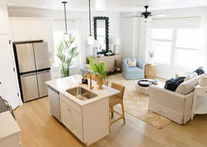 Kitchen featuring white cabinets, decorative light fixtures, stainless steel appliances, sink, and a center island with sink