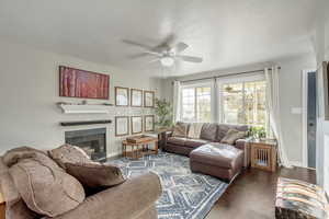 Living room featuring ceiling fan, dark hardwood / wood-style floors, and a textured ceiling