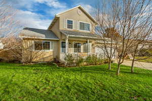 View of front of house with covered porch and a front lawn