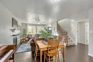 Dining area featuring ceiling fan, dark wood-type flooring, and a textured ceiling