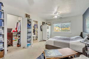 Bedroom featuring a walk in closet, a closet, ceiling fan, light colored carpet, and ensuite bathroom