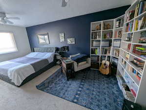 Carpeted bedroom featuring a textured ceiling and ceiling fan