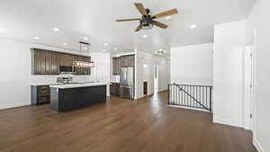 Kitchen featuring hanging light fixtures, dark hardwood / wood-style floors, stainless steel appliances, and an island with sink