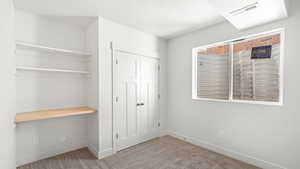 Unfurnished bedroom featuring a closet, built in desk, and light colored carpet