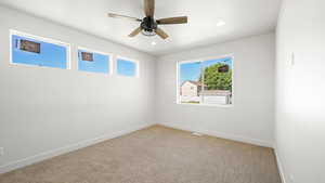 Carpeted spare room featuring ceiling fan