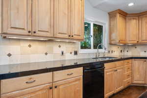 Kitchen featuring light brown cabinetry, dishwasher, sink, and decorative backsplash