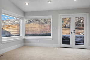 Doorway to outside with french doors, carpet floors, and a textured ceiling