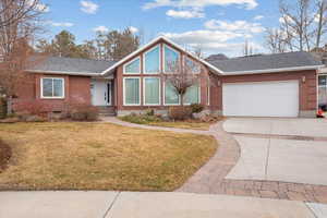 View of front facade featuring a garage and a front lawn