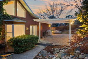 Patio terrace at dusk with a hot tub and a pergola