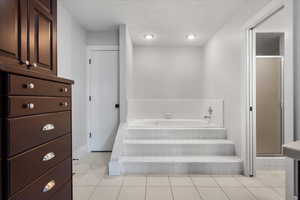 Bathroom with tile patterned floors, shower with separate bathtub, and a textured ceiling