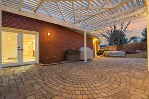 Patio terrace at dusk featuring a jacuzzi, a pergola, a grill, and french doors