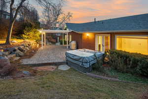 Back house at dusk with a lawn, a patio, and a pergola