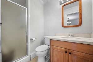 Bathroom with vanity, tile patterned flooring, a shower with shower door, and toilet