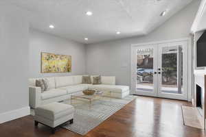 Living room with french doors, hardwood / wood-style floors, and a textured ceiling